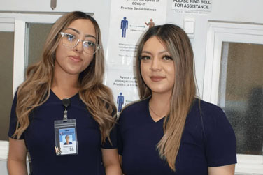 Two women standing next to each other in front of a sign.