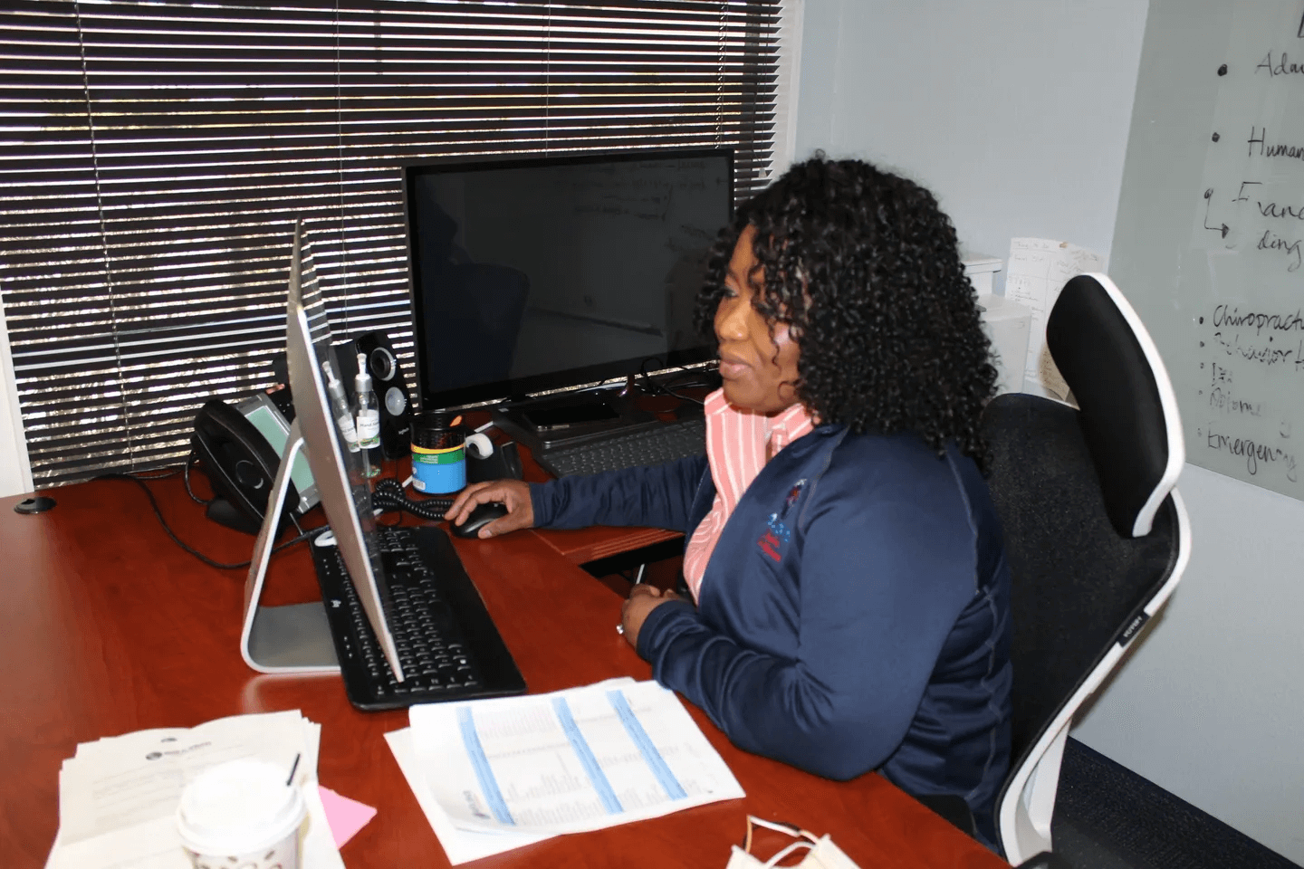 A woman sitting at a table with two laptops.